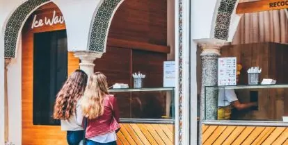two people standing in front of open storefront