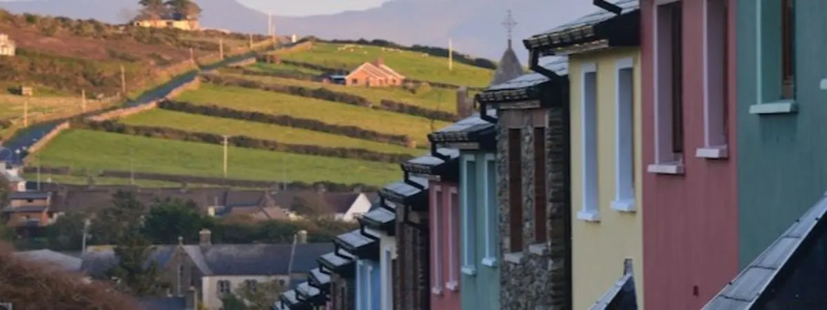 colorful houses with grass and mountains in background