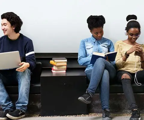 Students sitting in front of whiteboard working independently, chatting, etc.