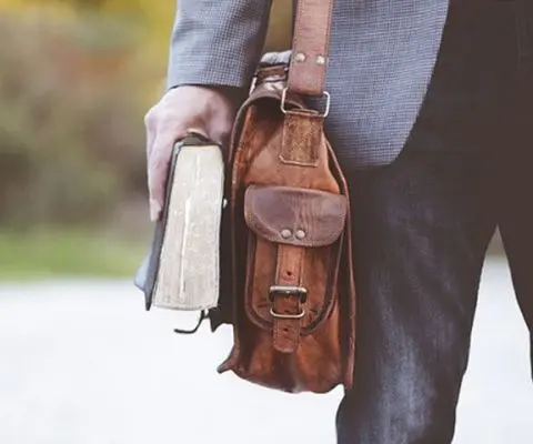man carrying a bag and a book