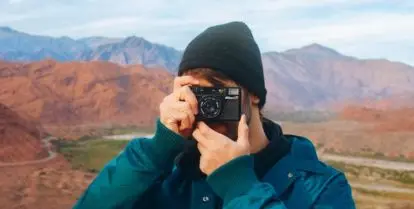 person holding camera in front of valley and mountains