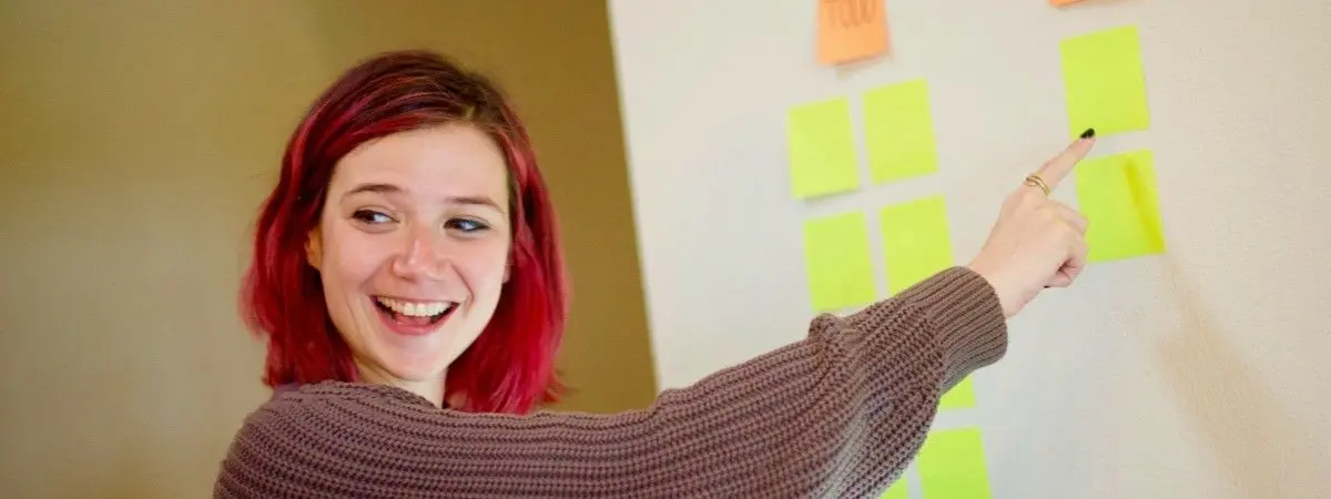 smiling person pointing at bright squares of paper on white background
