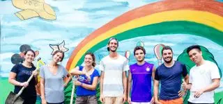 Volunteers in front of rainbow mural