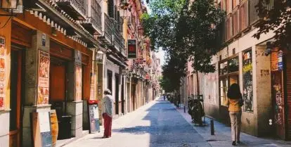 person walking on street between rows of buildings