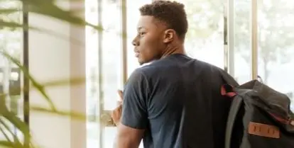 person-wearing-backpack holding-open-glass-door-featured-photo