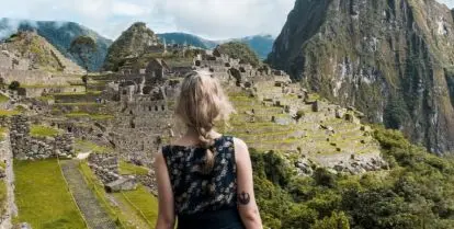 person facing Machu Picchu under blue sky with white clouds