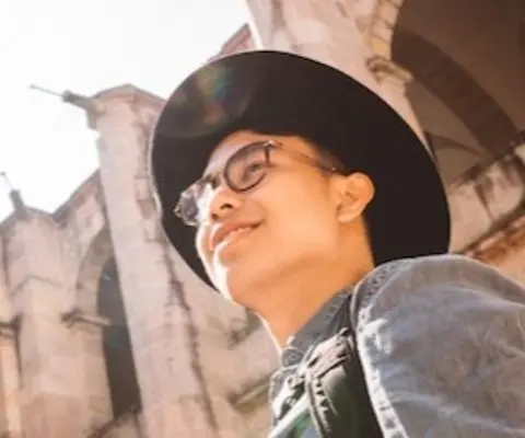 person wearing hat smiling and looking up at building