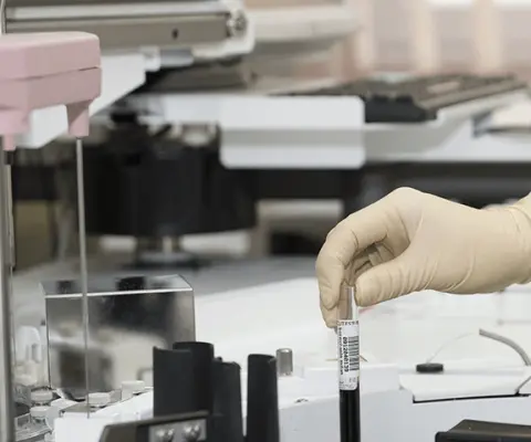 woman in white scrubs working with a centrifuge