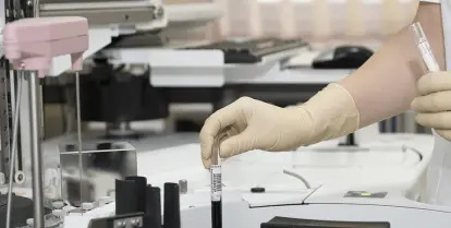 woman in white scrubs working with a centrifuge