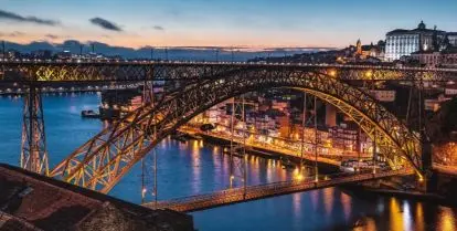 bridge over water and city buildings at night