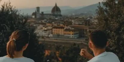 two people sitting near green trees overlooking Florence architecture in the background